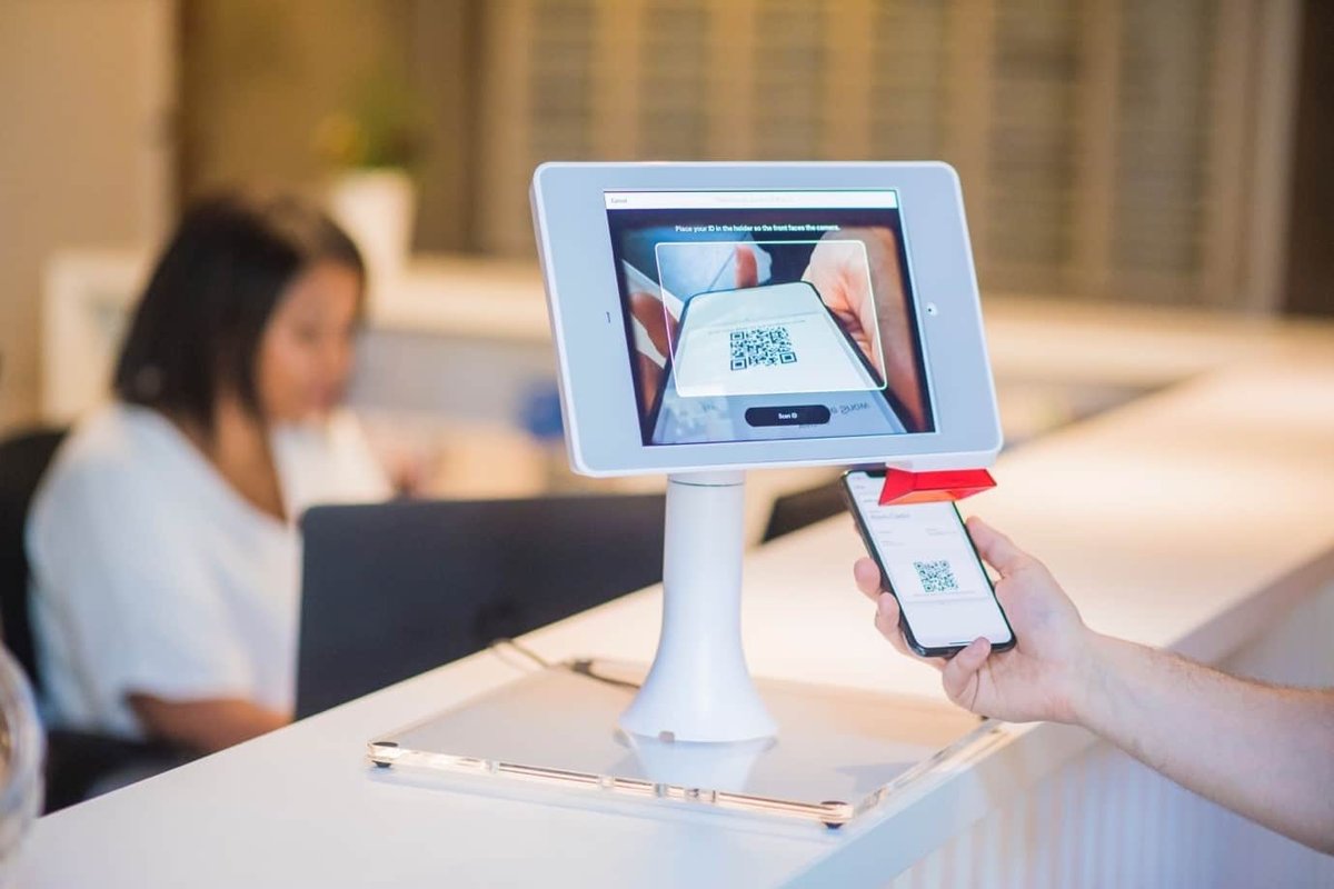 Phone showing a QR code held up to a tablet kiosk camera