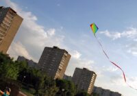 Rainbow diamond kite with a long red ribbon tail flying high