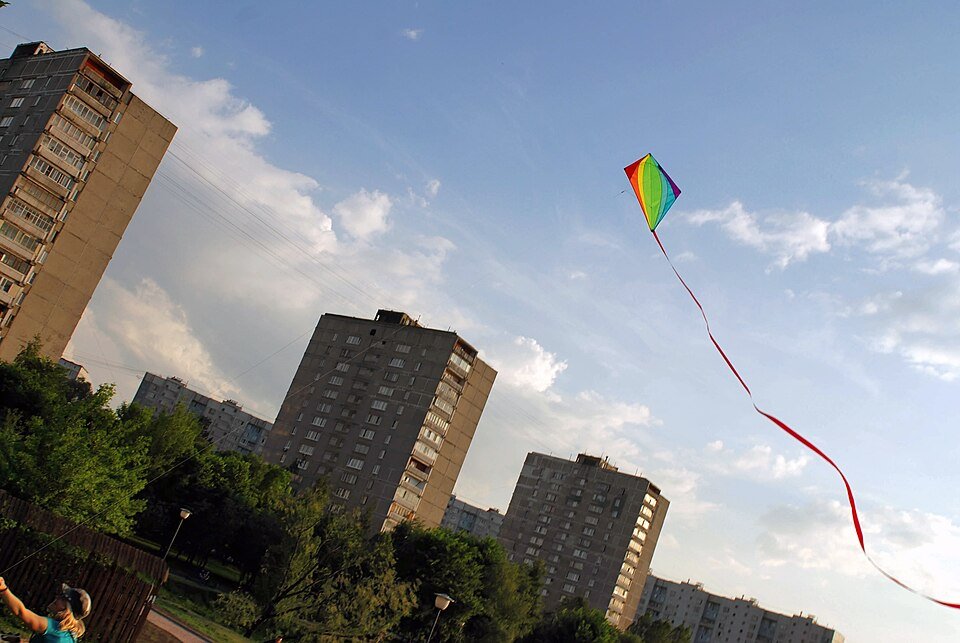 Rainbow diamond kite with a long red ribbon tail flying high