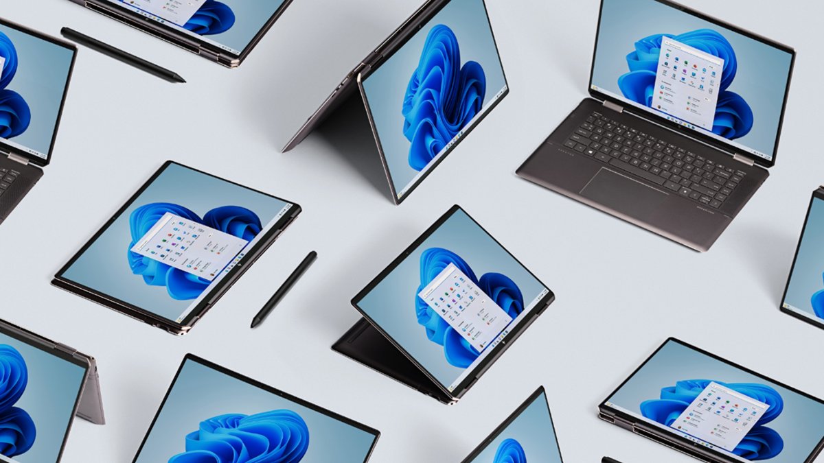 Several Windows 11 laptops and tablets arranged on a light surface