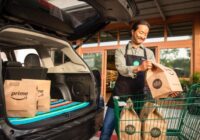 Whole Foods staff member loading Prime grocery bags into a car