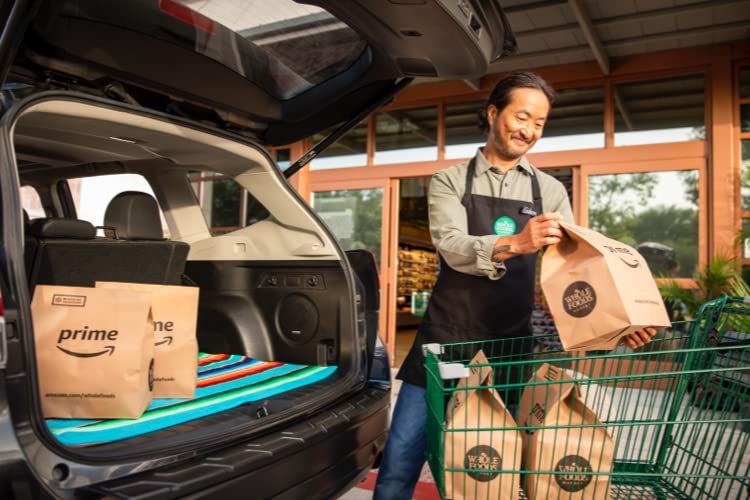 Whole Foods staff member loading Prime grocery bags into a car